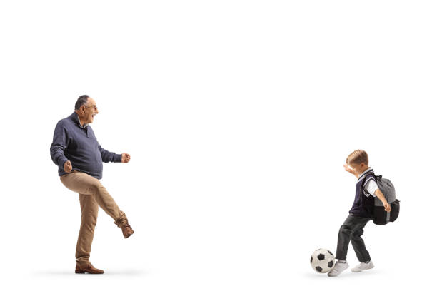 Mature man playing football with a schoolboy isolated on white background