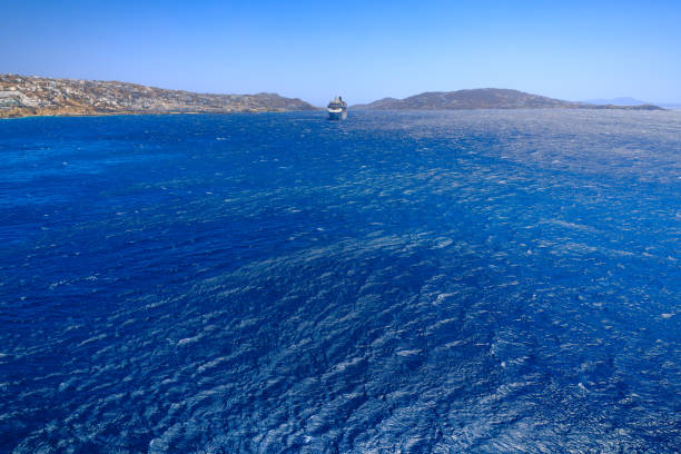 Scenery of rocky coastline: azure waters of the Aegean Sea vith cliff, waves and wind.