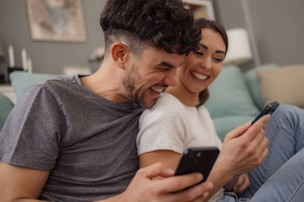 istock Young cheerful couple using cell phone at home. 2152163348