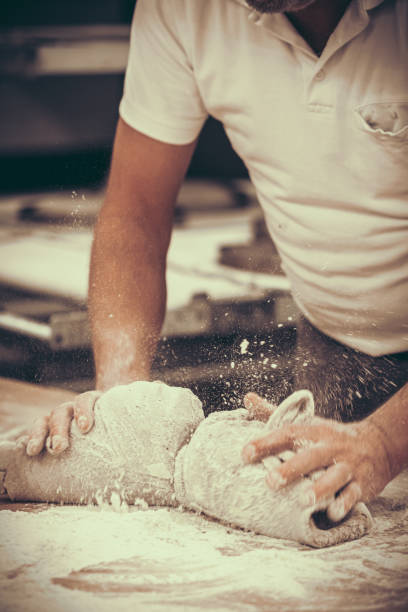 istock A baker kneads bread dough in the bakery. Vintage style with grain. Vertical. 2152163544