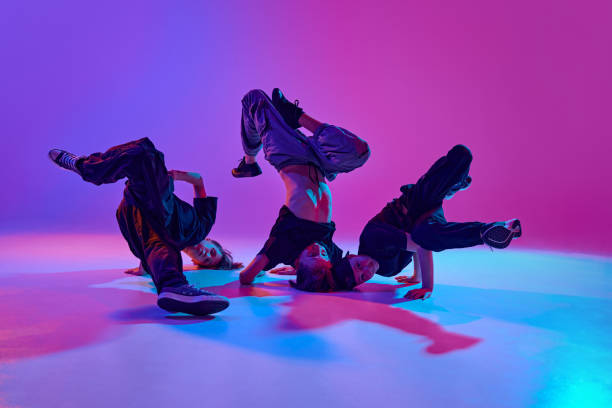 istock Urban dance performance. High-energy dance performance by three young boys in mixed neon light against vibrant gradient background. 2152164027