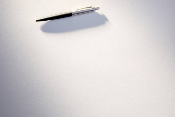 A sleek silver and black pen rests on an untouched white sheet, implying preparation for writing.