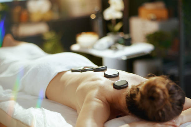 istock woman having hot stone massage and laying on massage table 2152170212