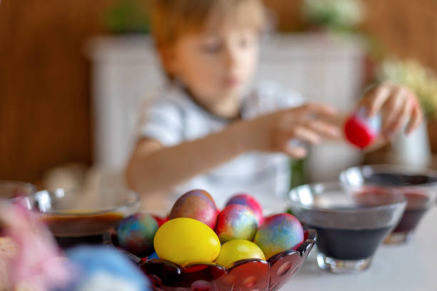 istock Beautiful blond child, boy, coloring and painting eggs for Easter at home 2152171227