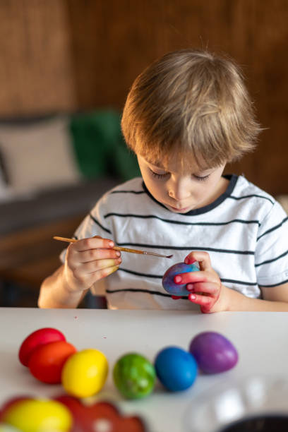 istock Beautiful blond child, boy, coloring and painting eggs for Easter at home 2152171239