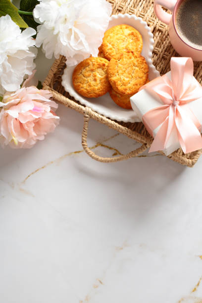 istock Romantic breakfast top view. Flat lay composition with wicker tray with cookies, coffee cup, gift box, flowers on marble table. 2152173274