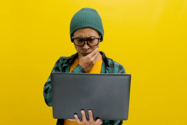 istock Asian freelance worker appears puzzled as he gazes at his laptop while working remotely from home 2152173528
