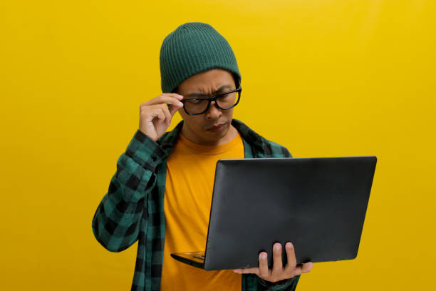 istock Asian freelance worker appears puzzled as he gazes at his laptop while working remotely from home 2152173604