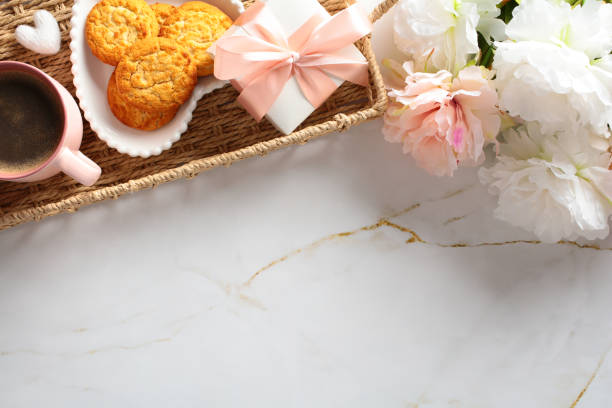 istock Top view cozy table with wicker tray with gift box, flowers, cup of coffee, cookies. 2152173621