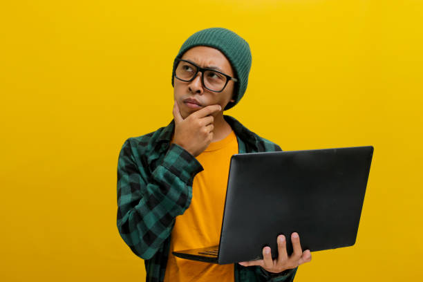 istock Asian freelance worker appears puzzled as he gazes at his laptop while working remotely from home 2152173656