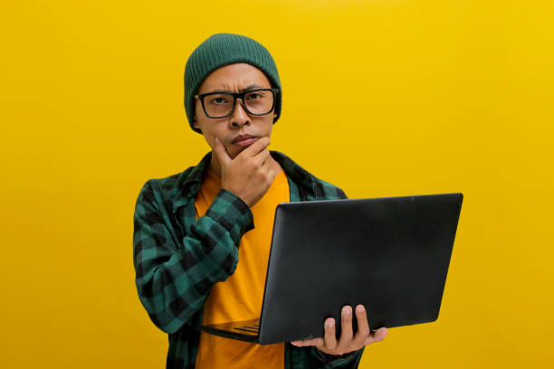 istock Asian freelance worker appears puzzled as he gazes at his laptop while working remotely from home 2152173730