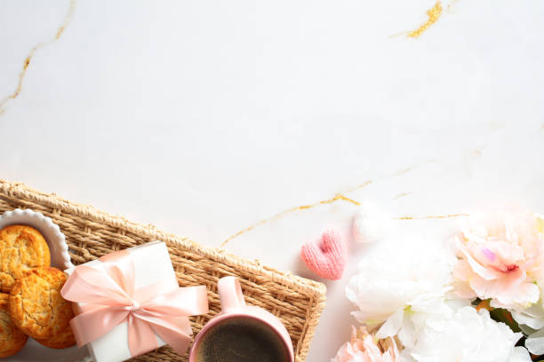 istock Wicker tray with breakfast, gift box and flowers on marble table. Top view. 2152173740