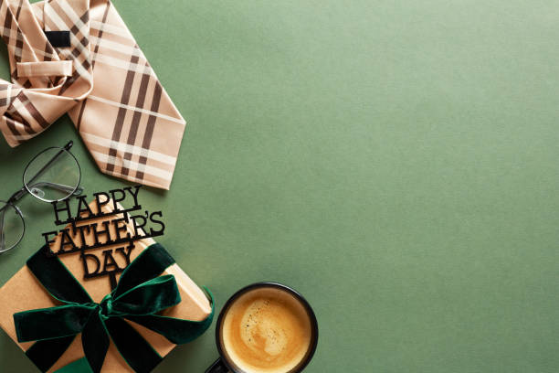 istock Happy Fathers Day concept. Flat lay composition with necktie, gift box with green ribbon bow, glasses, coffee cup and dark green background. 2152174373
