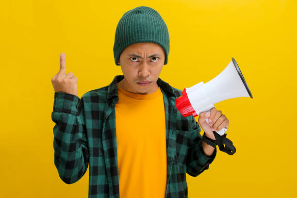 istock Angry Asian Man Flips the Bird While Yelling into Megaphone for Change or Protests 2152175552