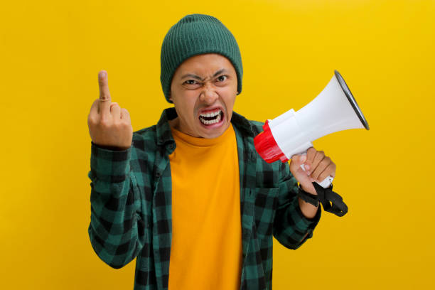 istock Angry Asian Man Flips the Bird While Yelling into Megaphone for Change or Protests 2152175635