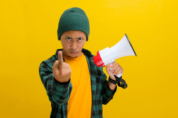 istock Angry Asian Man Flips the Bird While Yelling into Megaphone for Change or Protests 2152175652