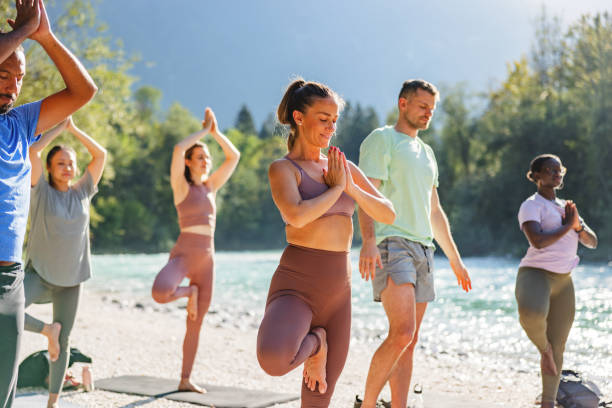 istock Group of People Practicing Yoga by the River in Nature 2152176245
