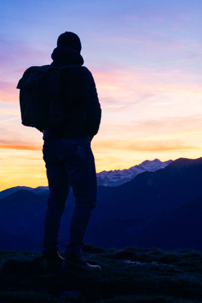 istock Silhouette of a man with a backpack contemplates a beautiful landscape at sunset. 2152176756