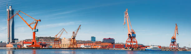 Gothenburg, Sweden- April 9, 2023: Gothenburg port loading cranes panorama against a backdrop of skyscrapers and blue skies, concept of maritime and industry.