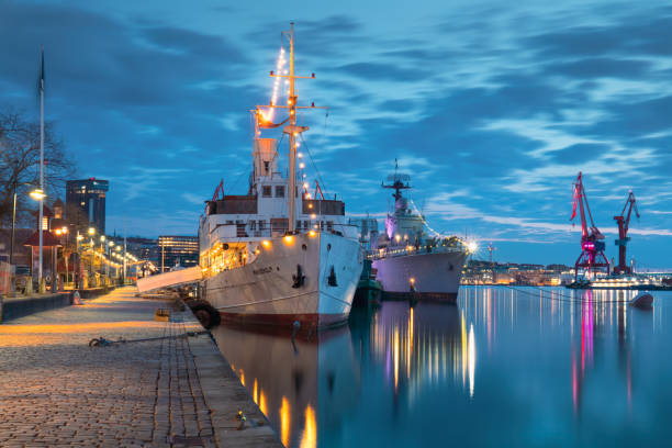 Gothenburg, Sweden- April 8, 2023: Twilight in Gothenburg harbor, with docked ships and cranes silhouetted against the vibrant evening sky, concept of maritime activity.