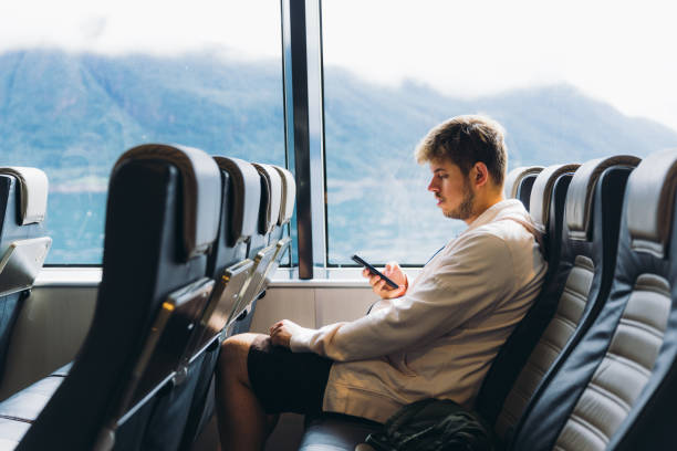 istock Man Crossing Sea by Ferry Boat Using Smartphone with Mountain View 2152182069