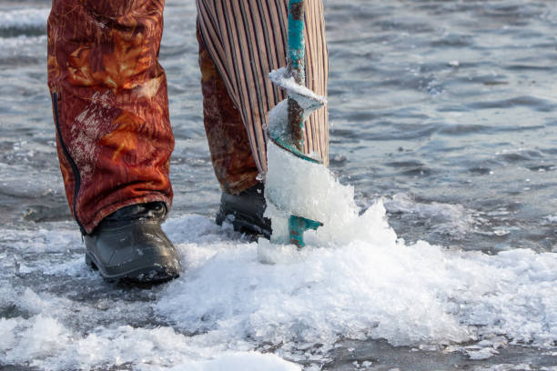istock A man with a drill on the ice while fishing 2152183717