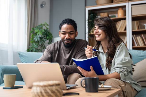 istock Positive hipster couple having fun while working together remotely at home using modern technology, cheerful young business male and female laughing. Businesspeople in home office Independence concept 2152186394