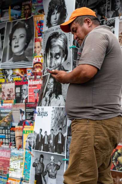 Mexico City, Mexico - March 29, 2023 - A man booping on his phone while walking in front of election posters on the street