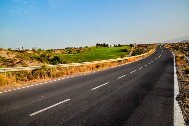 A road with a grassy area in the middle. The road is empty and the sky is clear