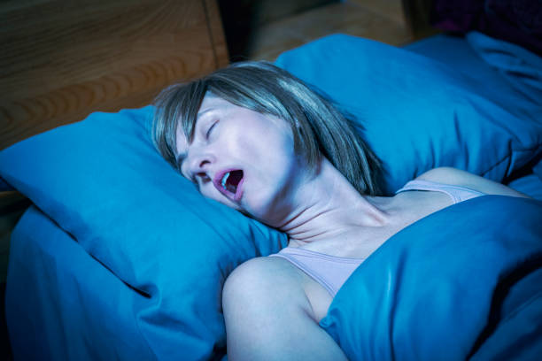 Middle Aged Woman With Mouth Open Snoring in Bed at Night