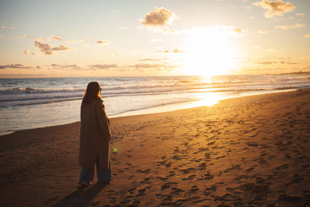 istock Woman enjoys evening walk by sea. 2152204208