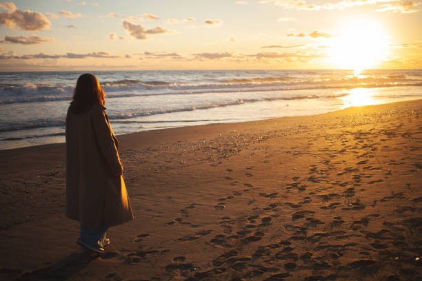 istock Lady walks along shore at twilight. 2152204209