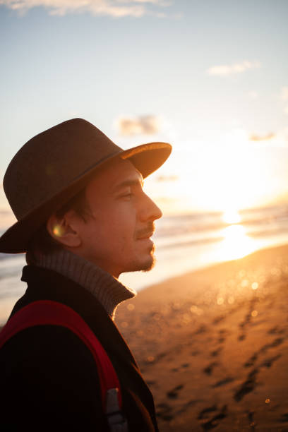 Lone man enjoys seaside stroll under golden sky