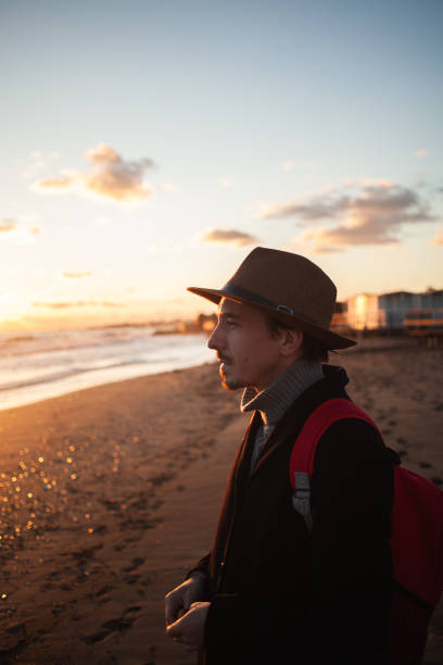 istock Man leisurely walks on sandy beach during sunset. 2152204256