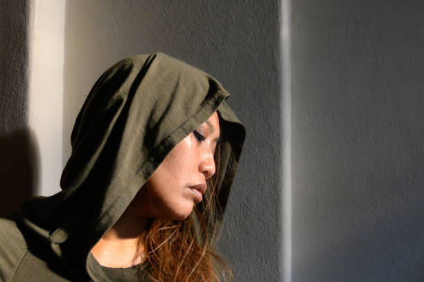 istock Solitude in Sunlight: Woman in Hood Captured in Sharp Sunlit Contrast 2152206237