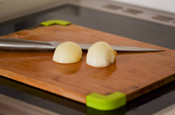 Three of raw peeled onion on wooden cutting board. Preparing fresh vegetable ingredients for a homemade meal. Slicing food for a onion ring.
