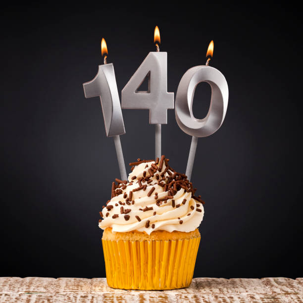 istock Birthday candle number 140 - Anniversary cupcake on black background 2152210582