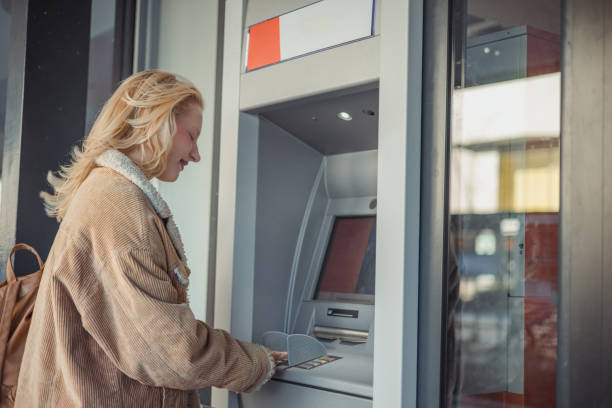 istock Young girl at atm machine doing deposit or withdrawal 2152213027