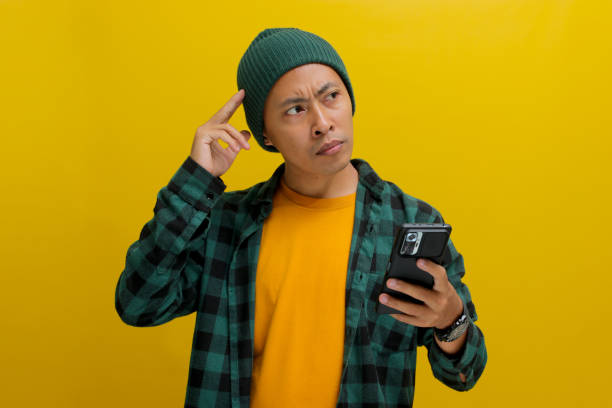 istock Pensive Asian man holds a mobile phone 2152213241