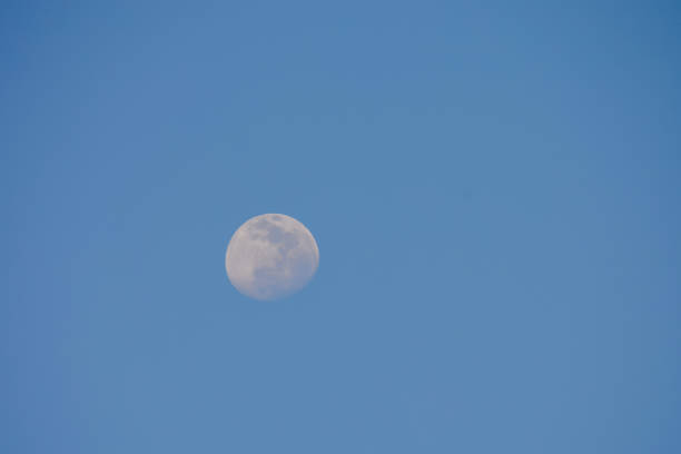 A large moon is in the sky above a clear blue sky. The moon is the only object in the image, and it is the main focus of the photo