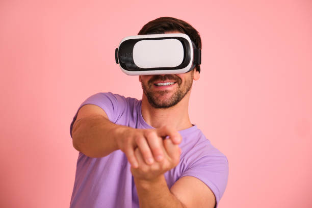 A man wearing a purple shirt is playing a sport video game with a virtual reality headset on. He is probably playing tennis or golf.