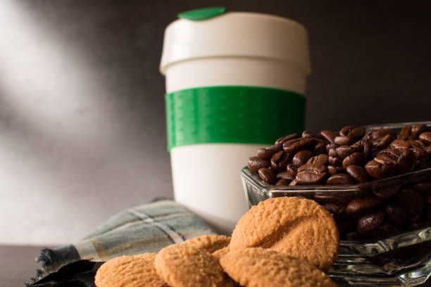 Coffee beans, cookies and plastic thermos for hot drinks on black table