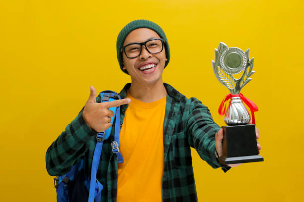 istock A young Asian male student pointing at his trophy 2152221864