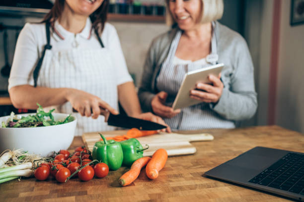 istock Two women using laptop while cooking healthy meal in the kitchen. 2152226516