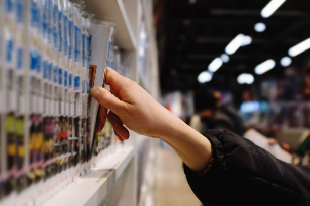 A person is reaching for a book on a shelf in a store.