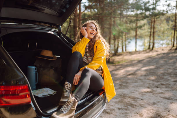 istock Young woman enjoying nature sitting in open trunk. 2152233590