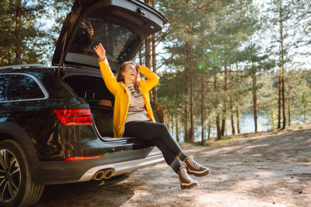 istock Young woman enjoying nature sitting in open trunk. 2152233593