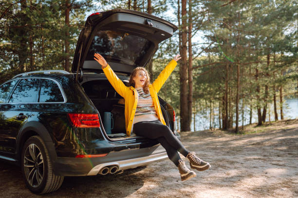 istock Young woman enjoying nature sitting in open trunk. 2152233595