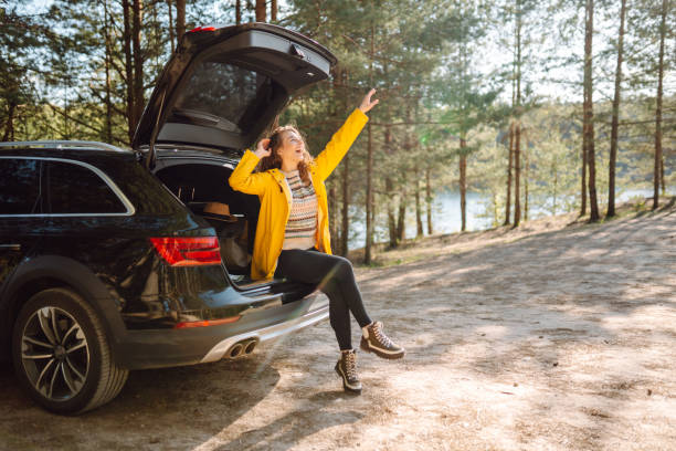 istock Young woman enjoying nature sitting in open trunk. 2152233606