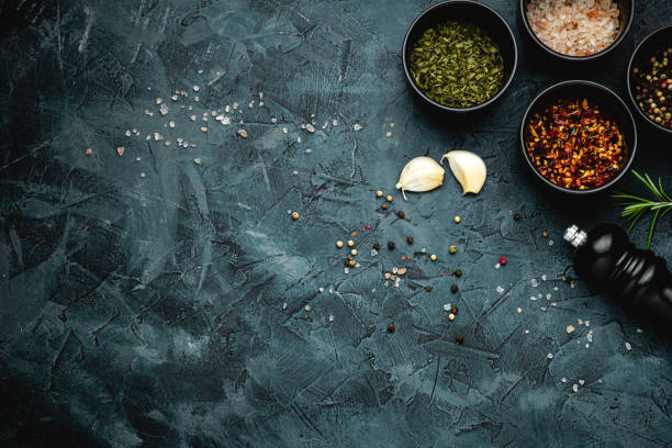 Dark stone kitchen background with spices, herbs and kitchen utensils. Free space for text. Top view. Rustic style.